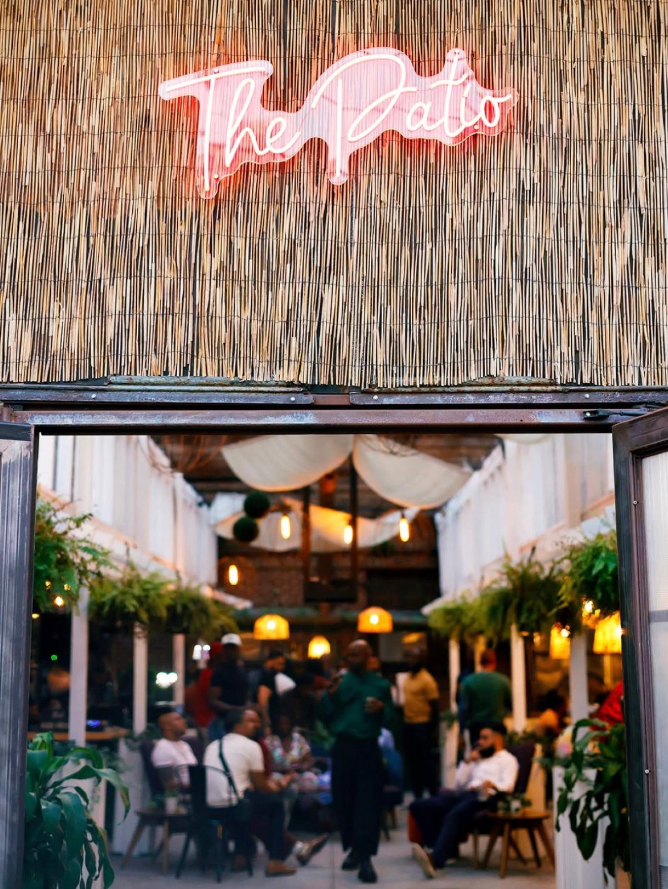 Pink neon &lsquo;The Patio&rsquo; sign above the entrance to the open-air room